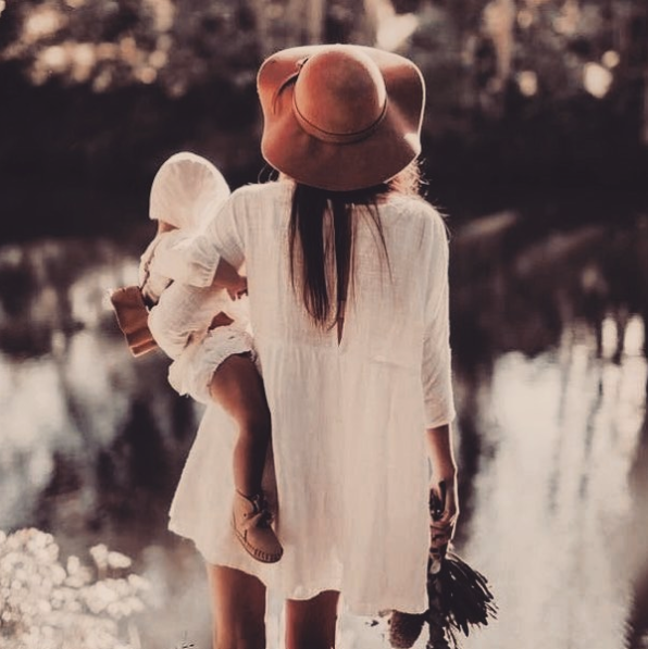 Anya gyermekével az ölében sétál a természetben.